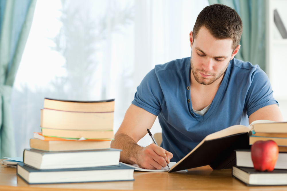 Young student preparing for an exam, writing notes and studying.