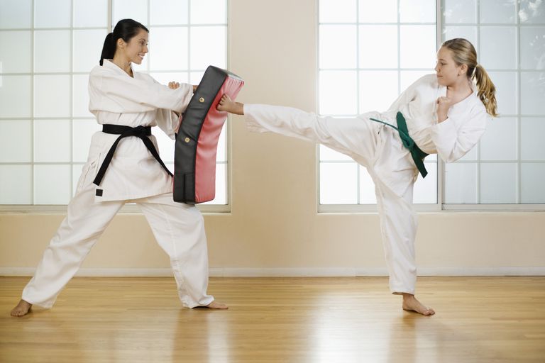 An Image showing a young girl trying to defending her opponent by holding an equipment.