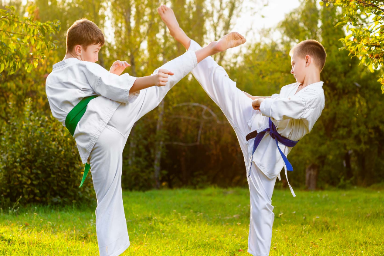 An Image of Two Boys Training Martial Arts Against Outdoor Background.